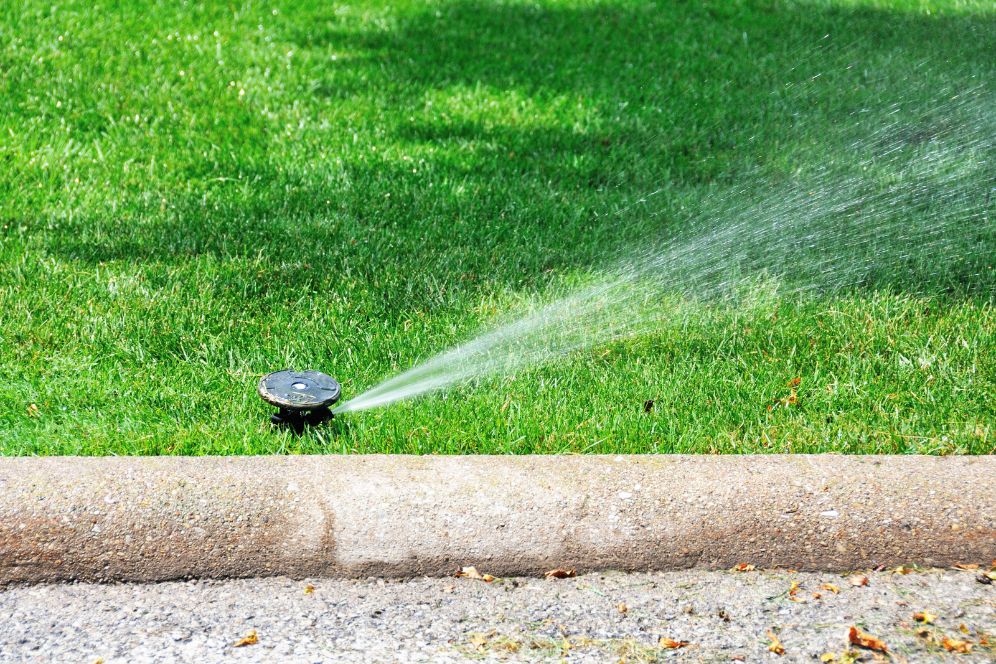 A lawn sprinkler actively waters a vibrant green lawn, representing a lawn irrigation service in Chicago, IL.